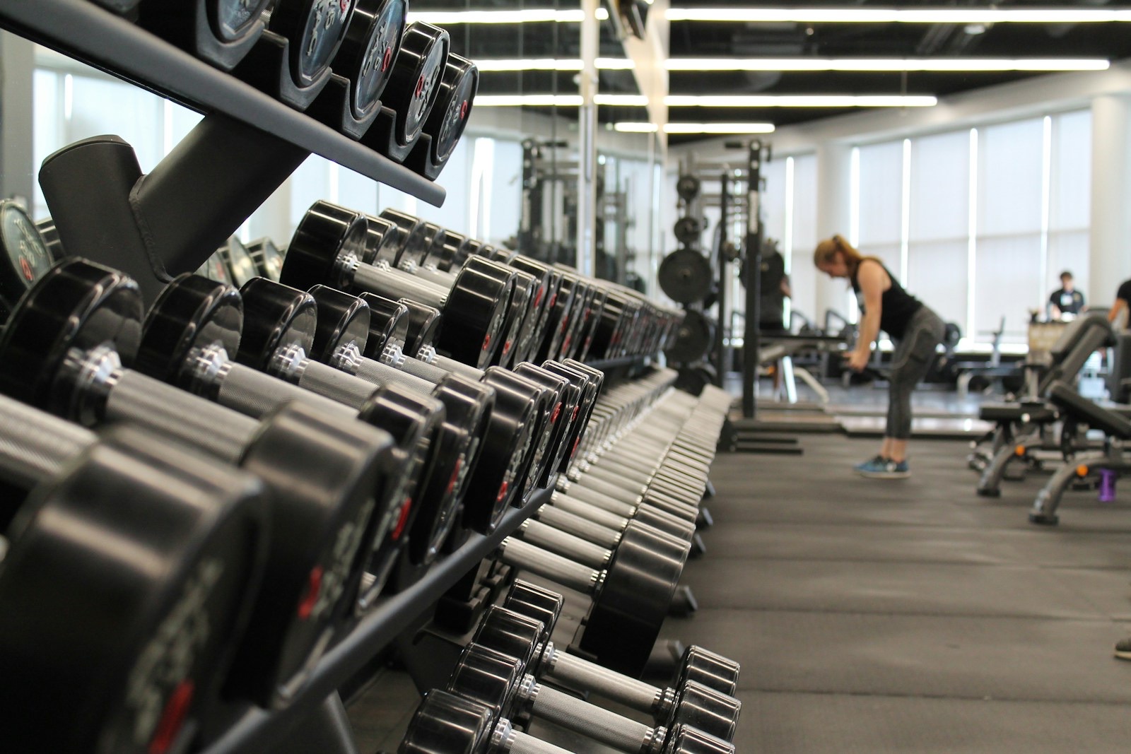 A person writing in a notebook beside weights in a gym